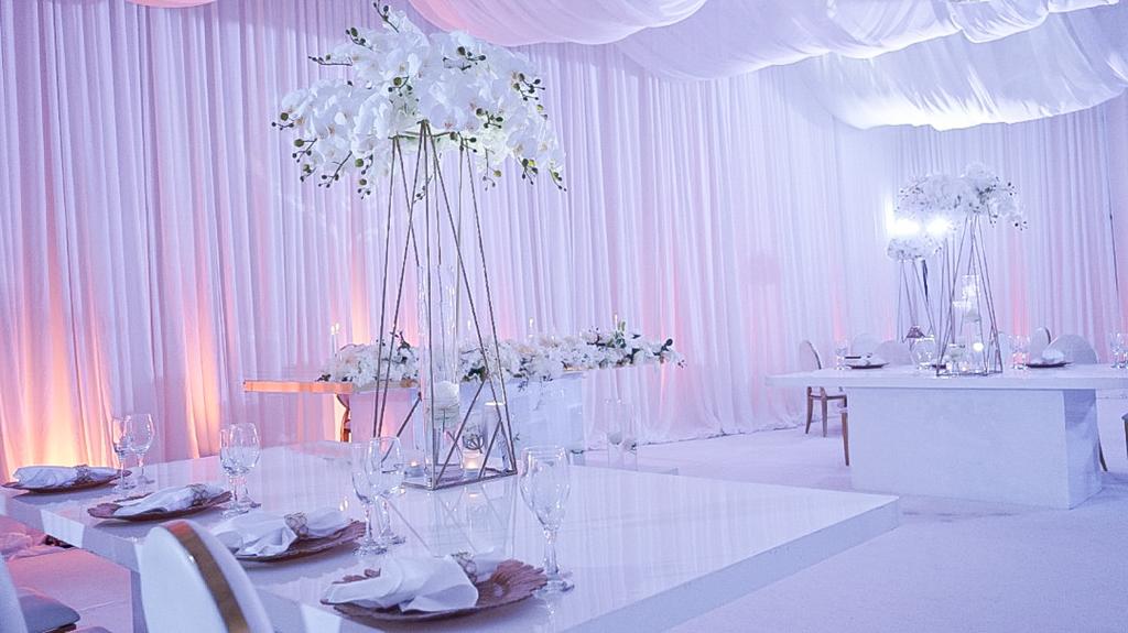 Draped venue interior with orchid centerpieces and crystal table settings